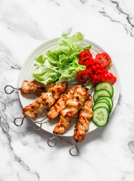 Brochetas satay de pollo con salsa de soja y yogur de mantequilla de maní con ensalada de verduras frescas sobre un fondo claro vista superior Deliciosas tapas