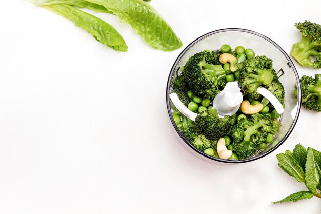 Foto el brócoli de guisantes verdes y las nueces de caju en el cuenco de la licuadora