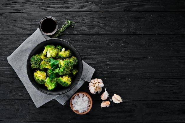 Foto brócoli hervido en un plato negro sobre un fondo negro vista superior espacio libre para el texto