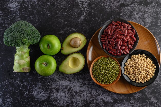 Brócoli, manzana, aguacate y legumbres sobre un fondo de suelo de cemento negro