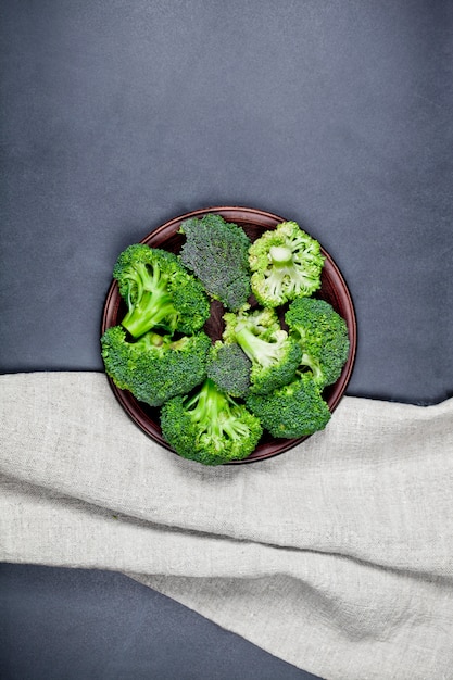 Brócoli orgánico verde fresco en plato marrón y servilleta de lino