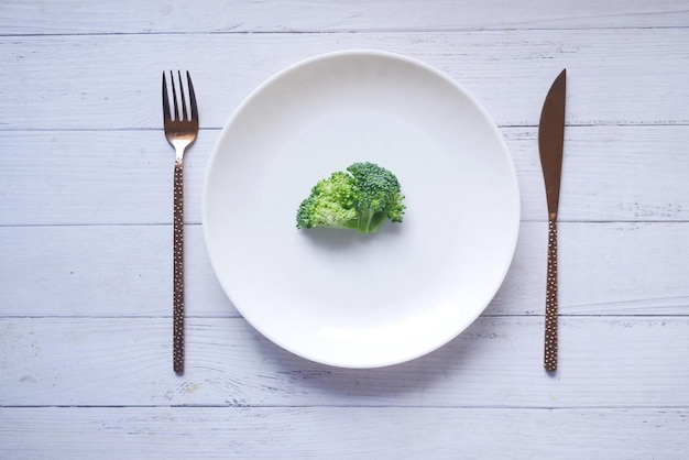 Brócoli en un plato con cubiertos en la mesa