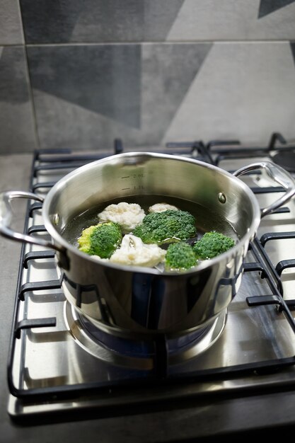 Brócolis e couve-flor cozidos em uma panela cinza no fogão a gás