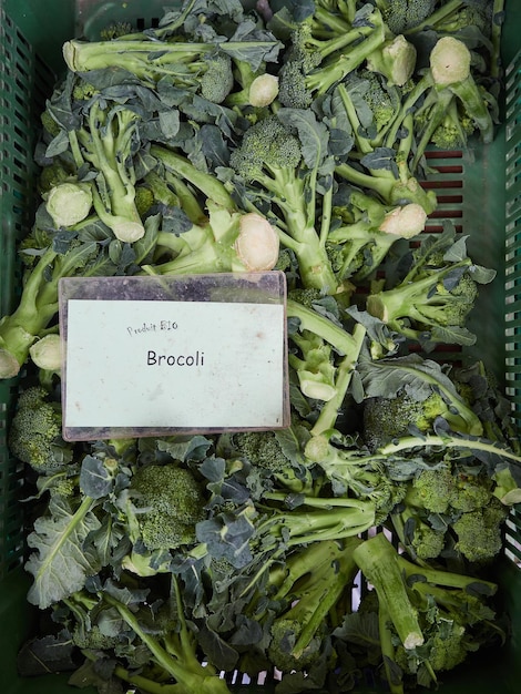 Brócolis orgânicos em caixa no mercado dos agricultores com texto francês "produit bio brocoli", produto bio brócolis. Vista do topo