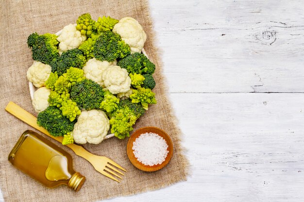 Brócolis sortido, romanesco e couve-flor. Ingrediente fresco e maduro para uma alimentação saudável. Fundo branco de tábuas de madeira, vista superior