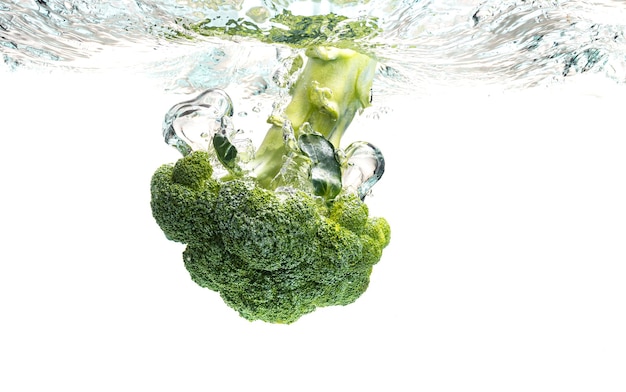 Brócolis verde caindo na água com salpicaduras em branco com bolhas de ar