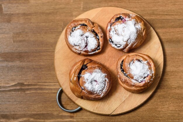 Brötchen mit Johannisbeeren mit Puderzucker überzogen auf ein Schneidebrett legen braun