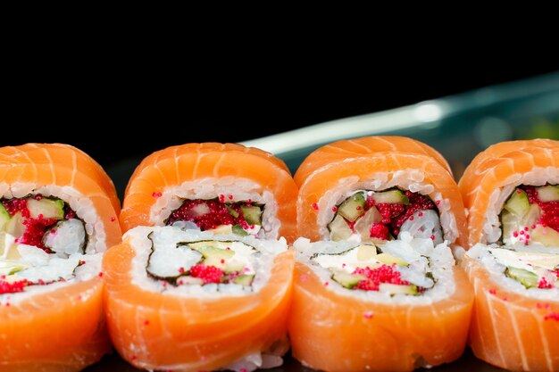 Brötchen mit Lachs, Tobiko-Kaviar, Avocado, Gurke, Nori-Nahaufnahme. Traditionelle japanische Küche.