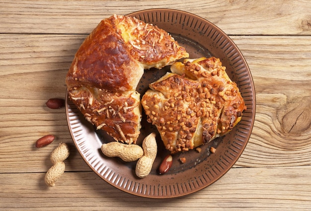 Brötchen mit Marmelade und Käse, bestreut mit gemahlenen Nüssen in der Platte auf Holzhintergrund Draufsicht