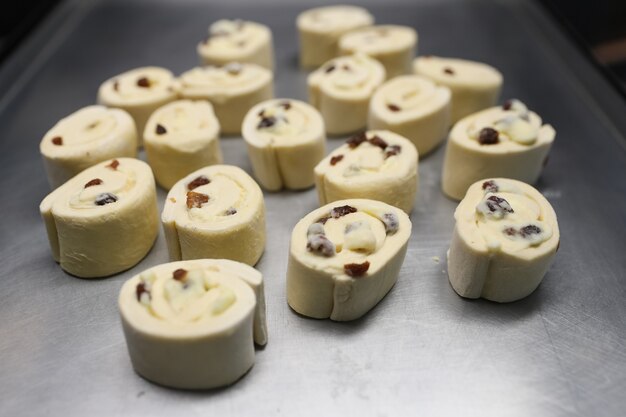 Brötchen mit Rosinen auf einem Backblech vor dem Backen im Ofen