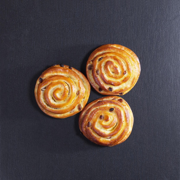 Brötchen mit Rosinen vor schwarzem Steinhintergrund, Draufsicht