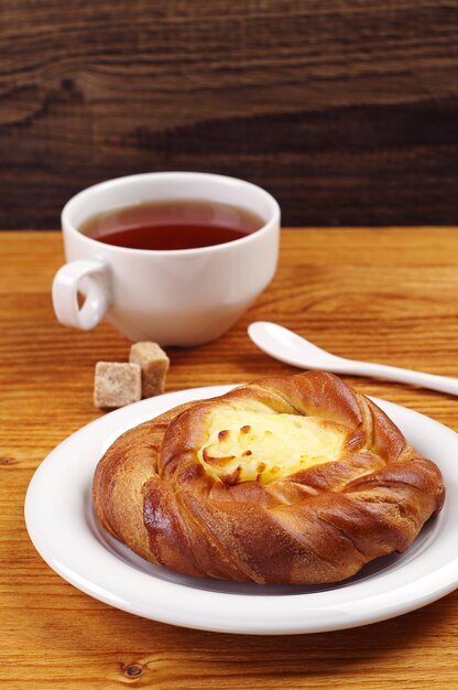 Brötchen mit Vanillesoße und Tee auf Holztisch