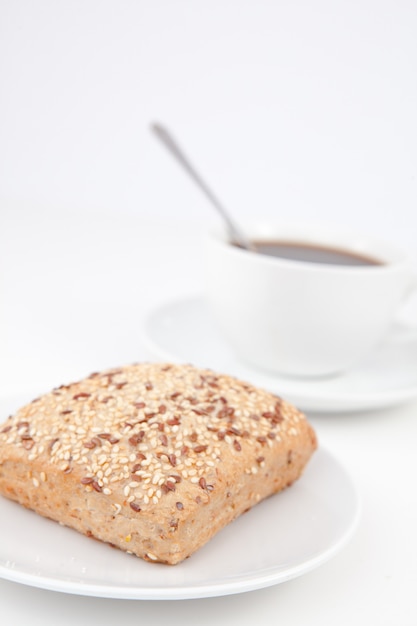 Brötchen und ein Tasse Kaffee mit einem Löffel auf weißen Platten