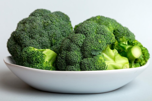 Brokkoli aus frischem grünem Brokkoli in einer Schüssel über farbigem Hintergrund in der Nähe von frischem Gemüse
