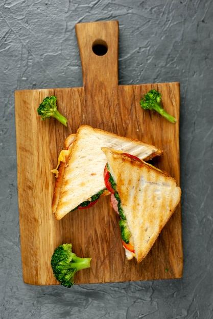 Brokkoli-Käse-Sandwiches auf Holzschneidebrett, auf Beton, Schieferhintergrund