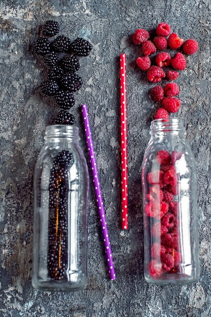 Brombeer- und Himbeerfrucht in Glasflaschen mit Strohhalmen