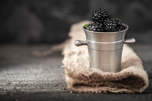 Brombeere in Metallschalen auf dunklem Hintergrund.