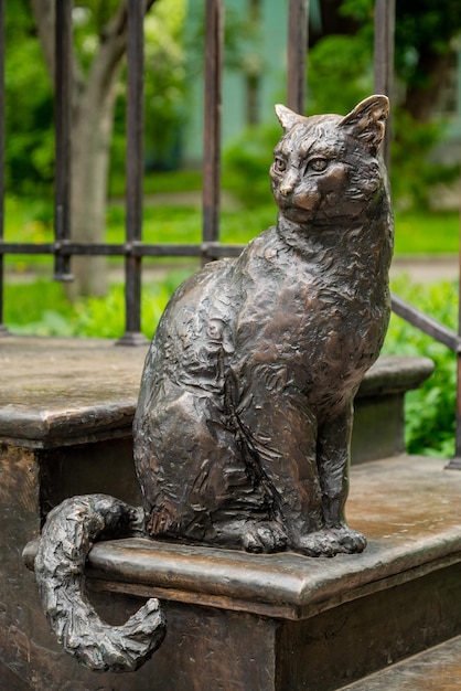 Bronzekatze, die auf Treppenstatue in der Stadtstraße sitzt