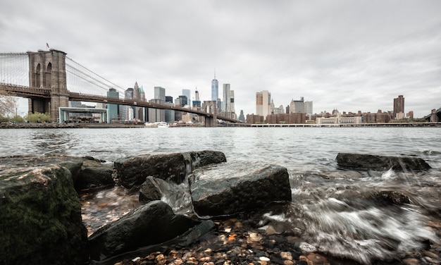 Brooklyn Bridge mit Felsen am Ufer des East River