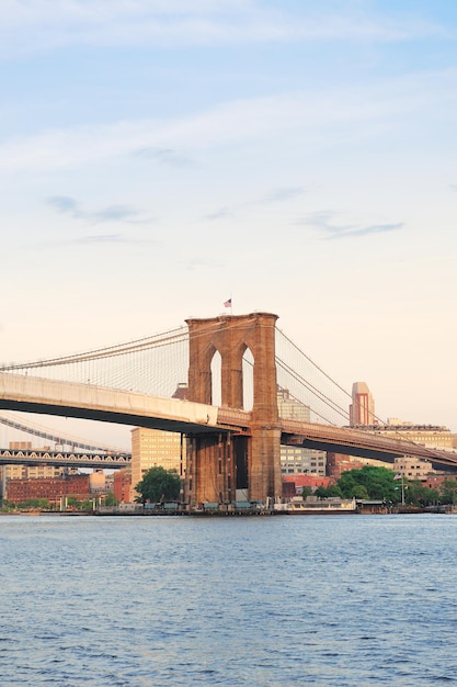Brooklyn Bridge über den East River gesehen von New York City Lower Manhattan Waterfront bei Sonnenuntergang.