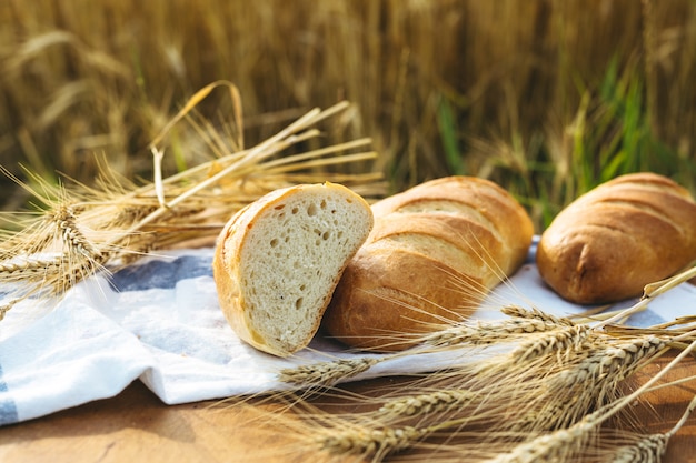 Brot auf dem Tisch und Weizen auf dem Gebiet des Weizens und des sonnigen Tages