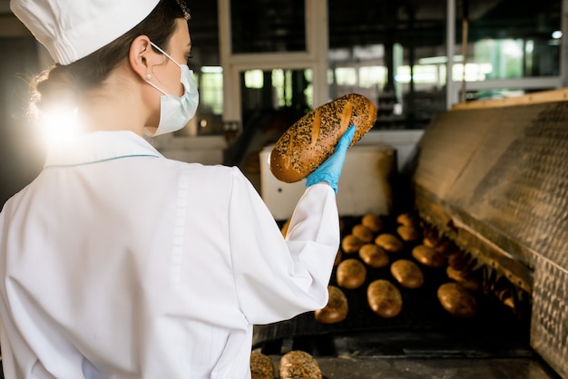 Brot. Brotproduktionslinie. Frau in Uniform. Hygienekontrolle.