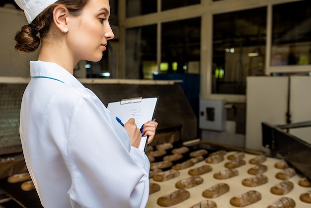 Brot. Brotproduktionslinie. Frau in Uniform. Hygienekontrolle.