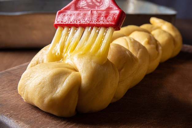 Brot, Ei über rohen Teig streichen, bereits in Form von Brot auf Holz.