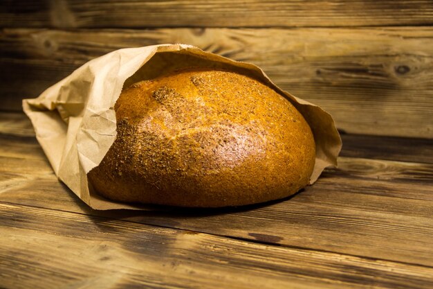 Brot in Papier verpackt auf Holztisch