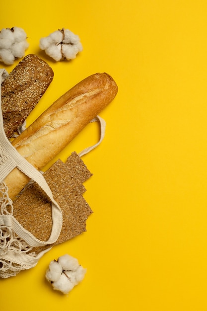 Brot in umweltfreundlicher Baumwolltasche auf gelber Oberfläche