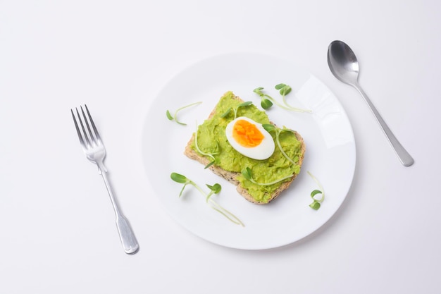 Brot mit Avocado, Gemüse, Obst und Ei auf weißem Hintergrund Gesundes Frühstückskonzept