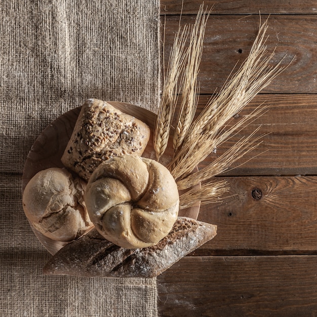 Brot mit den Weizenähren und Mehl auf hölzernem Brett, Draufsicht