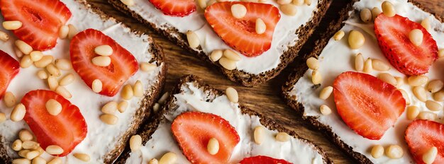 Brot mit Erdbeeren, Pinienkernen und Frischkäse auf Holz