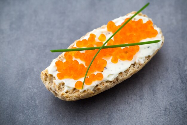 Brot mit frischem Frischkäse und rotem Kaviar auf dem Tisch.