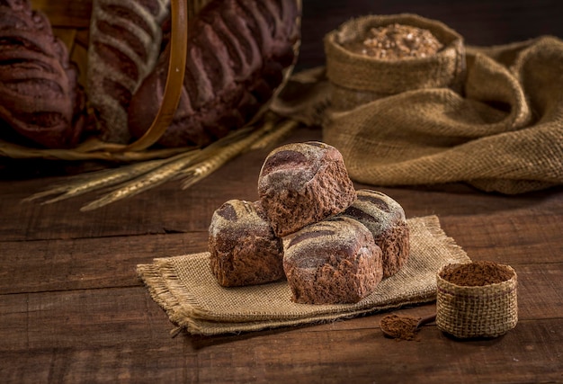 Brot mit Kakao und Schokolade auf rustikalem Stoff auf rustikalem Holztisch mit Zutaten.