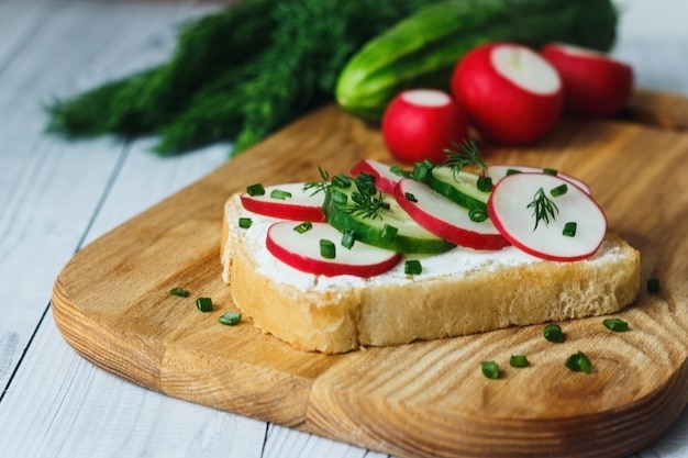 Brot mit Quark frischer Rettichgurke auf einem hölzernen Schneidebrettkonzept des gesunden Fitnessfrühstücks