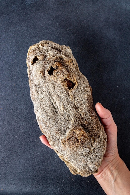 Brot mit Roggenmalz in weiblicher Hand auf blauem Hintergrund