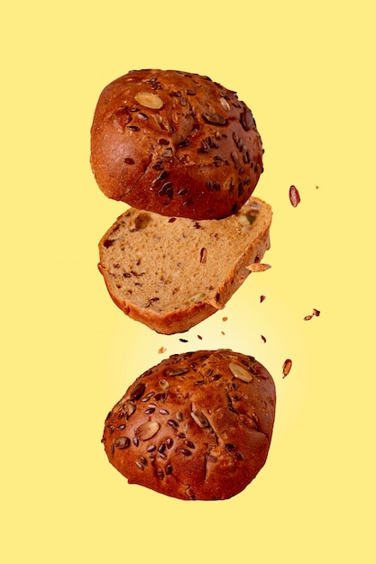 Brot mit Sonnenblumenkernen, die auf gelbem Hintergrund fliegen