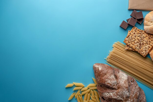 Brot, Nudeln, Schokolade auf blauem Hintergrund Draufsicht. Konzept des Online-Shoppings, frische Produkte mit Lieferung. Platz kopieren
