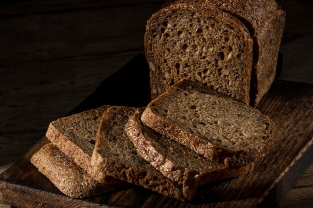 Brot, traditionelles hausgemachtes Brot, in Scheiben geschnitten auf rustikalem Holzhintergrund, Nahaufnahme.