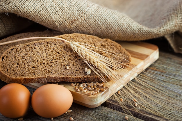 Brot und Weizen auf einem hölzernen Hintergrund