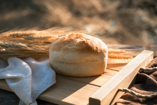 Brot und Weizen auf einer Holzkiste unter natürlichen Bedingungen in der Natur