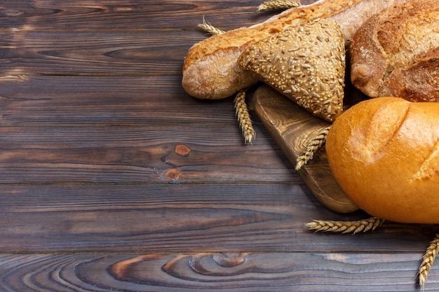 Brot und Weizen auf hölzernem Hintergrund. Draufsicht mit Kopienraum