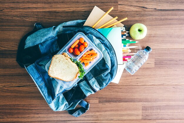 Brotdose mit Gemüse und Scheibe brot für ein gesundes Schulmittagessen auf Holztisch