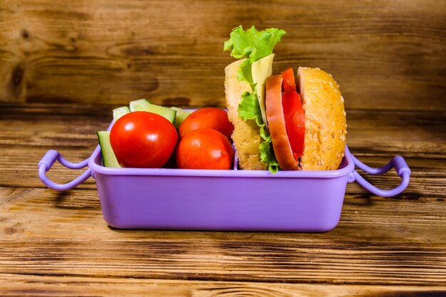 Foto brotdose mit hamburger-gurken und tomaten auf rustikalem holztisch