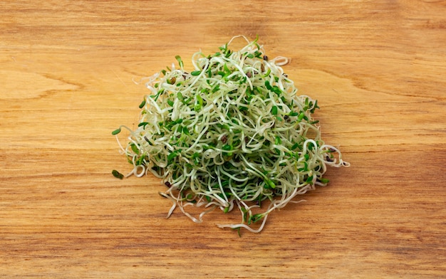 Brotes de alfalfa jóvenes orgánicos sobre una mesa de madera cerca de fondo