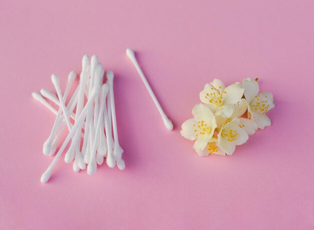 Brotes blancos cerca de flores de jazmín blancas en rosa claro de cerca Producto para el cuidado de la piel para la rutina de belleza diaria Concepto de belleza plano