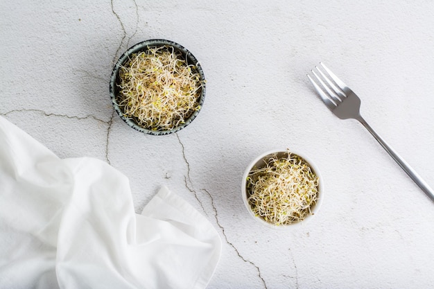 Brotes de trébol y alfalfa frescos para la comida en un recipiente sobre una mesa de luz Dieta orgánica de desintoxicación Vista superior