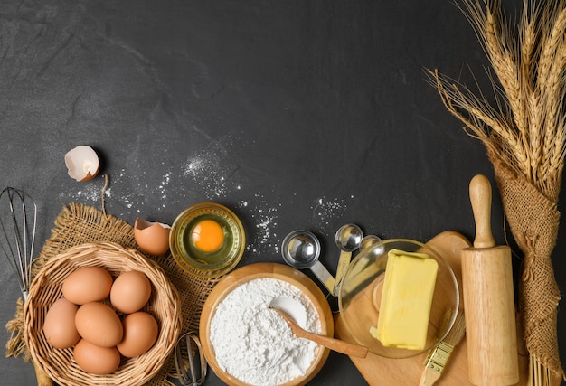 Brotmehl mit frischem Ei, ungesalzene Butter und Bäckereizubehör auf Holzhintergrund, bereiten Sie sich auf das hausgemachte Bäckereikonzept vor