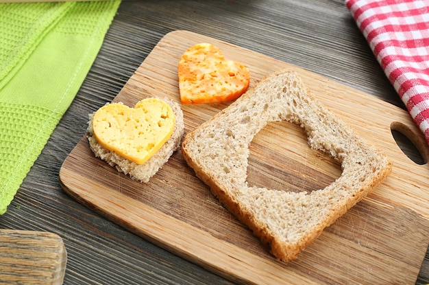 Brotscheibe mit Schnitt in Herzform und Käse auf dem Tisch aus nächster Nähe